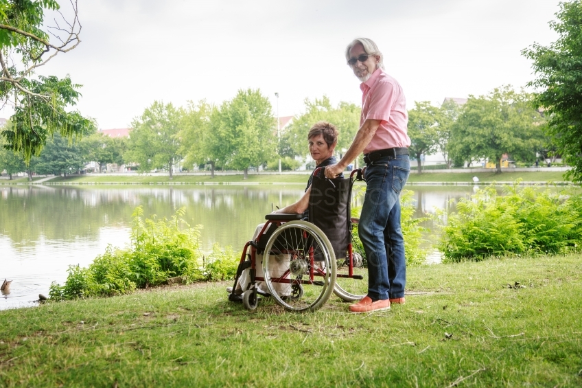 Frau im Rollstuhl mit ihrem Mann vor einem See 20160725