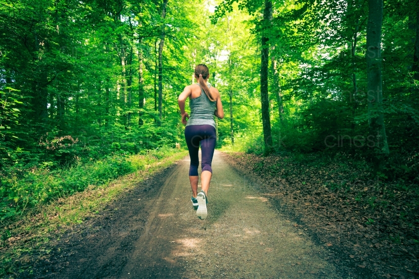 Frau joggt auf Waldweg Rückenansicht 20140717-0206
