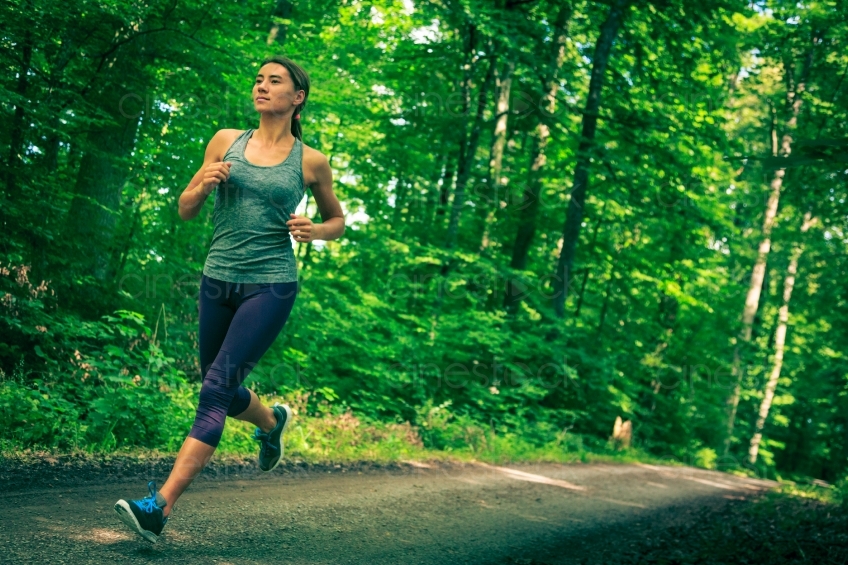 Frau joggt auf Waldweg Seitenansicht 20140717-0203 
