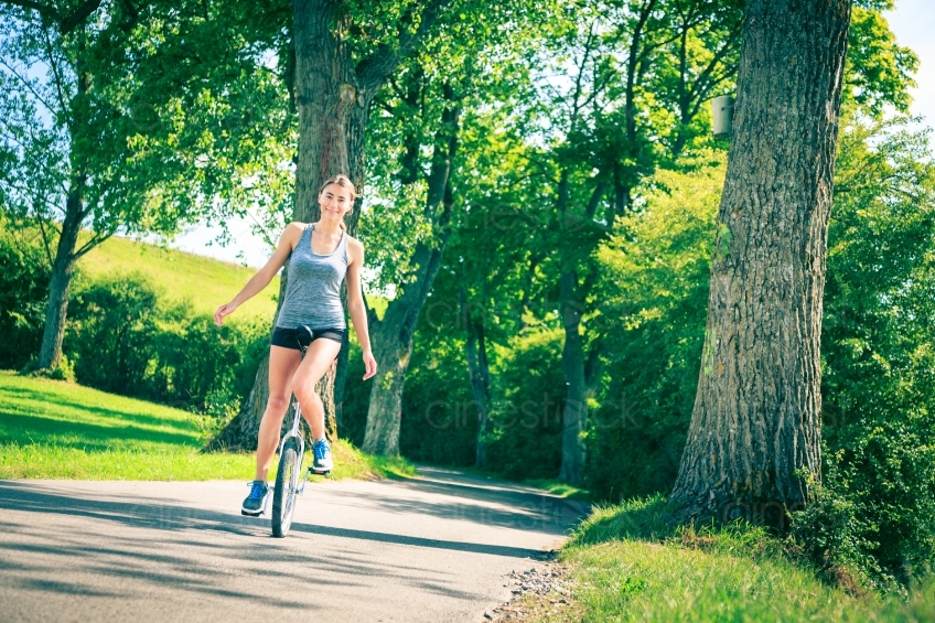 Junge Frau fährt Einrad in Natur 20140717-0234