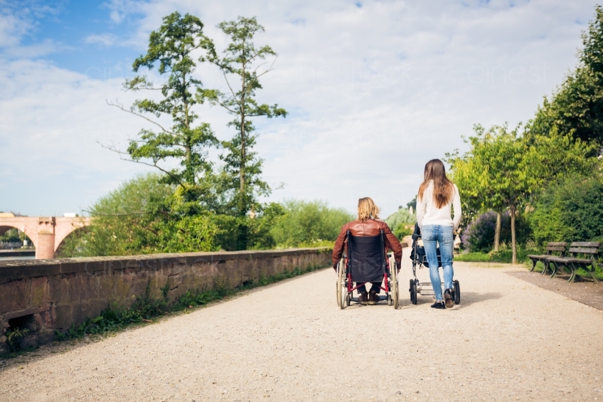 Rollstuhlfahrer neben Frau mit Kinderwagen Rückenansicht 20160810-0262 
