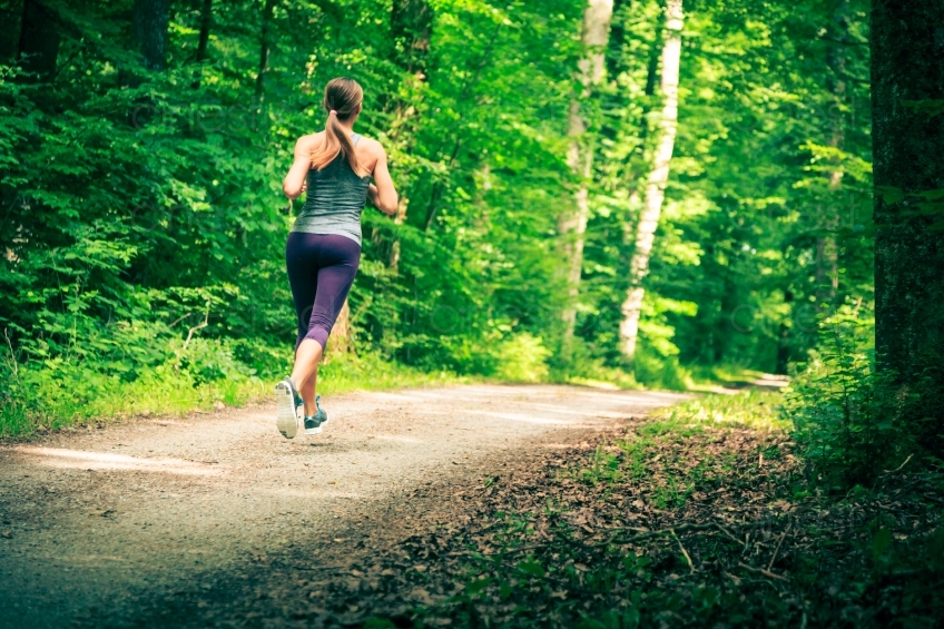 Rückenansicht von joggender Frau auf Waldweg 20140717-0189