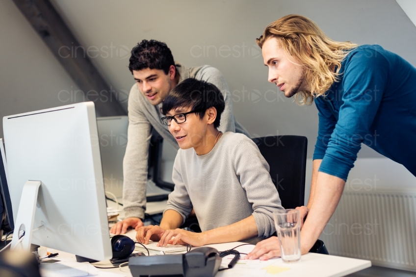 Drei Kollegen am Schreibtisch mit einem Bildschirm 20150510-0898 