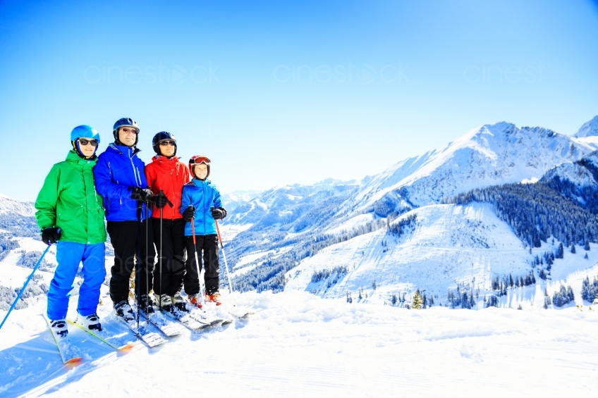 Familie steht mit Skiern auf einem schneebedecktem Berg 20130316