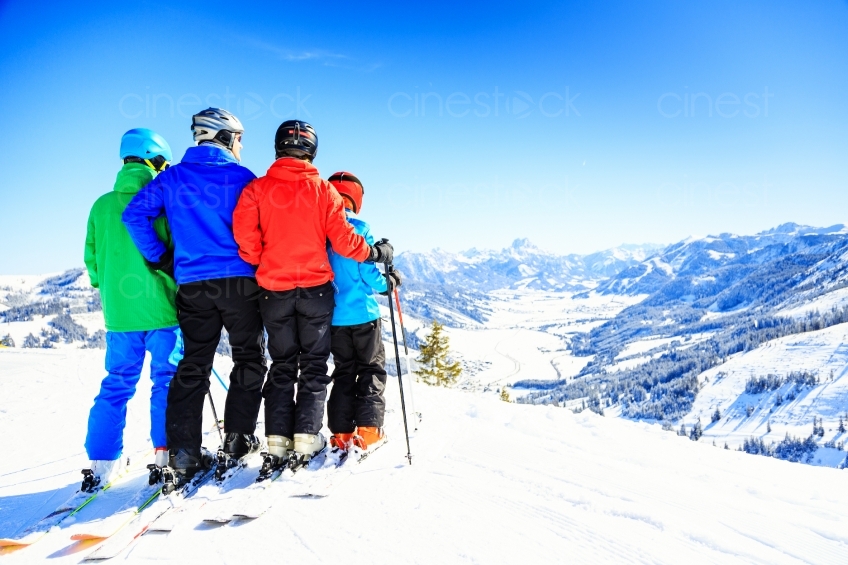 Familie steht mit Skiern auf einem schneebedecktem Berg 20130316