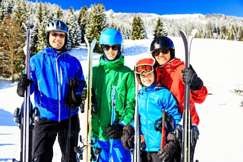 Familie steht mit Skiern vor schneebedecktem Wald 20130316
