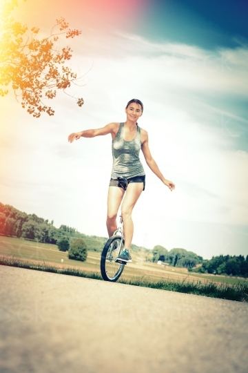 Frau balanciert auf Einrad aus Distanz 20140717-0255 