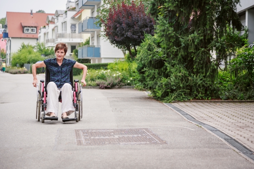 Frau fähtr Rollstuhl an Straße 20160725-0490
