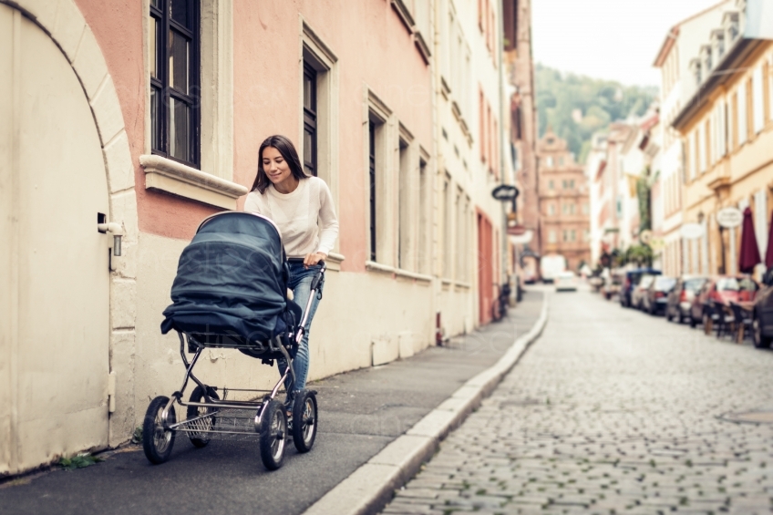Frau geht mit Baby im Kinderwagen spazieren 20160810