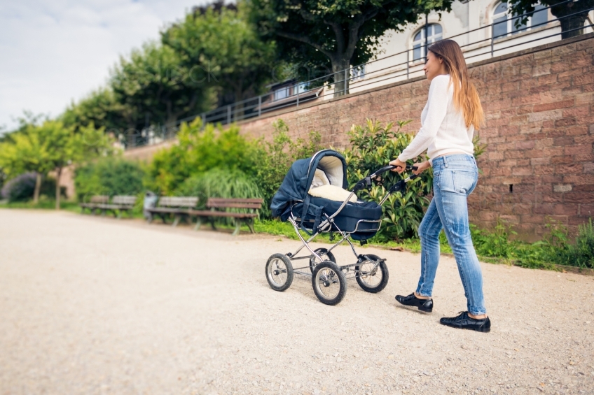 Frau geht mit Kind im Kinderwagen spazieren 20160810