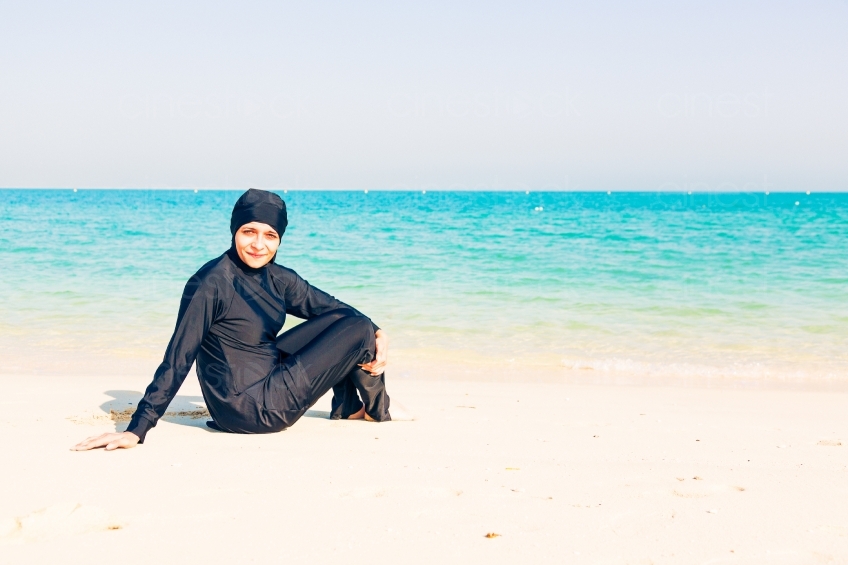 Frau im Burkini sitzt am Meer 20140313-3446