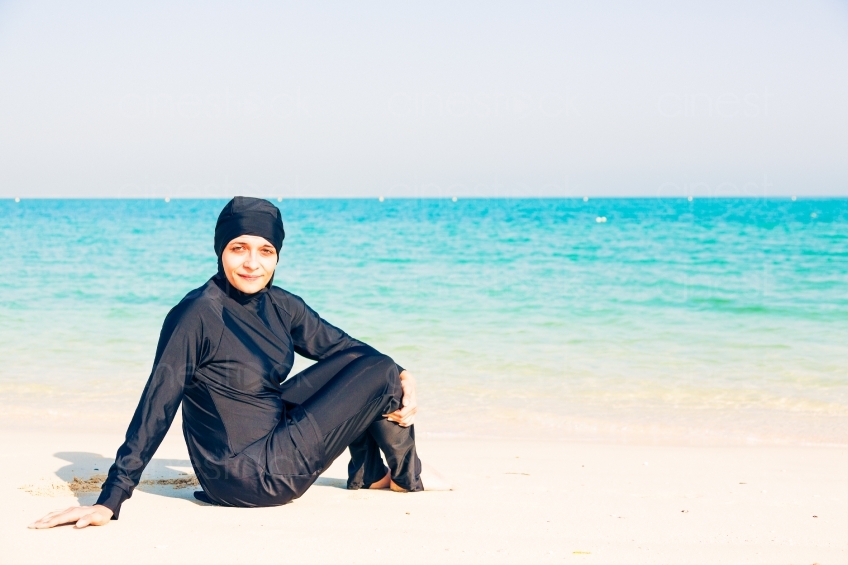 Frau im Burkini sitzt am Meer 20140313-3448 