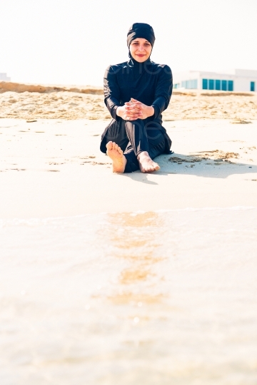 Frau im Burkini sitzt an Strand 20140313-3465