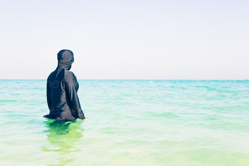Frau im Burkini steht im Meer Rückenansicht  20140313-3481