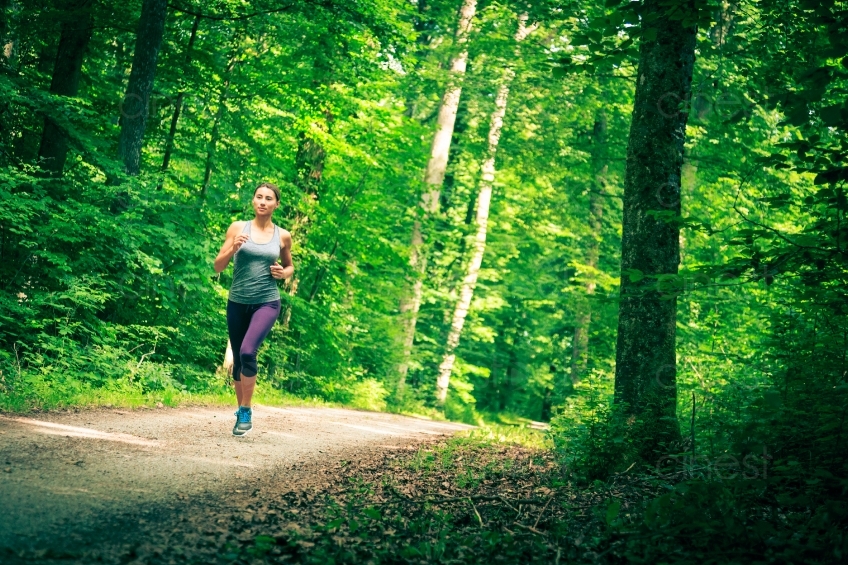 Frau joggt auf Waldweg aus Distanz 20140717-0198