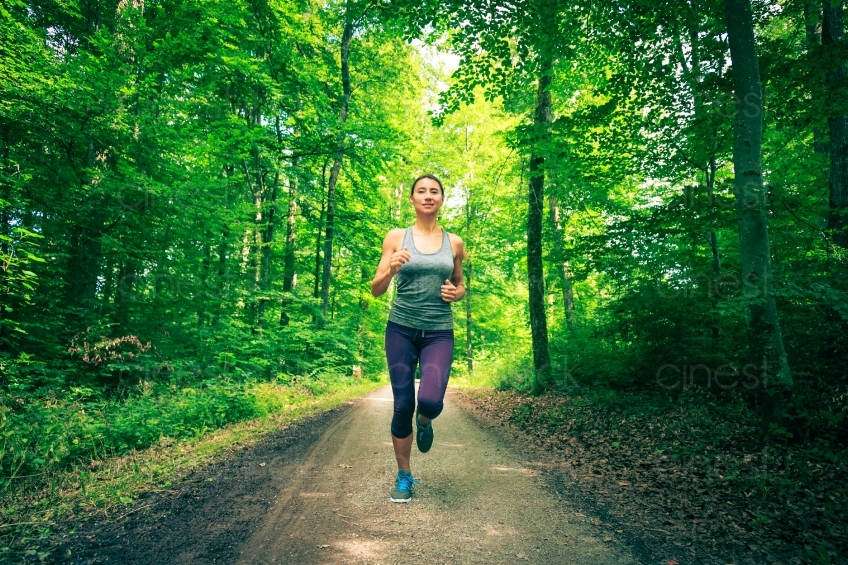 Frau joggt auf Waldweg zentral 20140717-0220