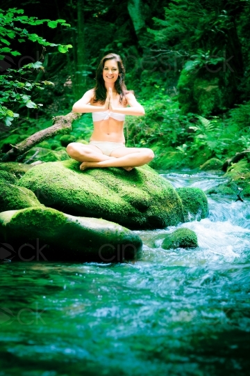 Frau meditiert auf einen Stein am Wasser 20120804