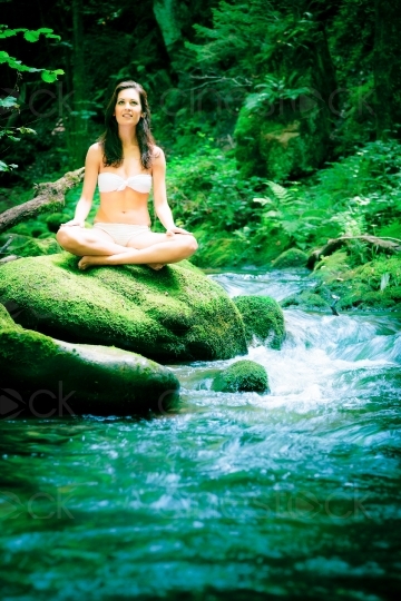 Frau meditiert auf einen Stein am Wasser 20120804