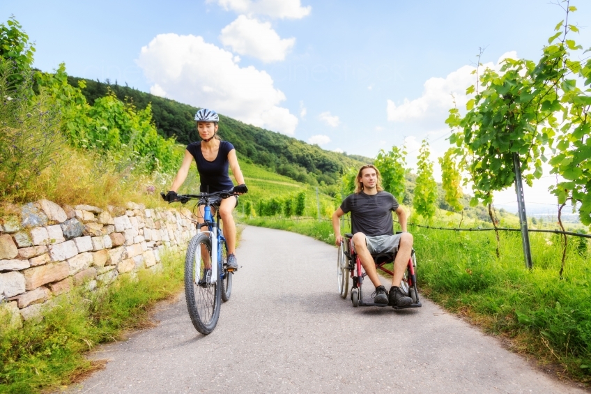 Frau mit Fahrrad  und Mann im Rollstuhl unterwegs 20160718