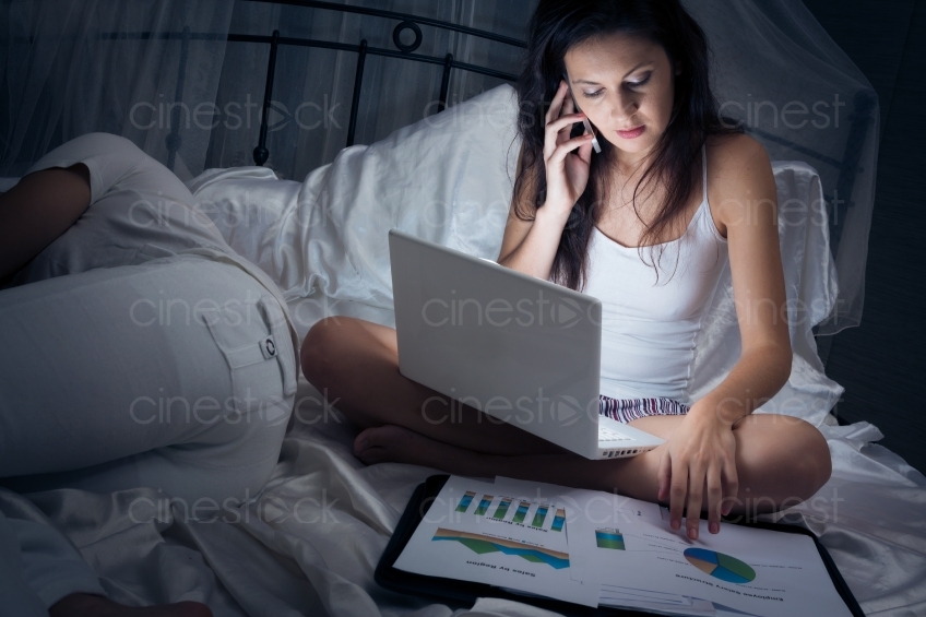 Frau mit Handy und Laptop im Bett 20121130-434