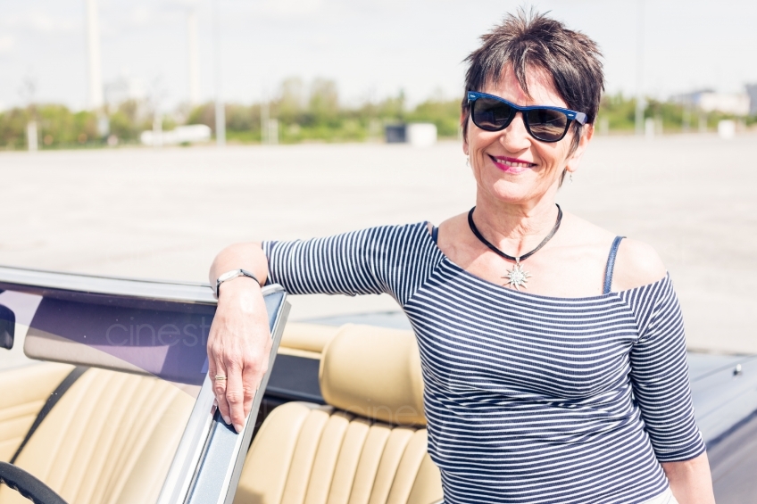 Frau mit Sonnenbrille lehnt an Cabrio 20150429-0340 
