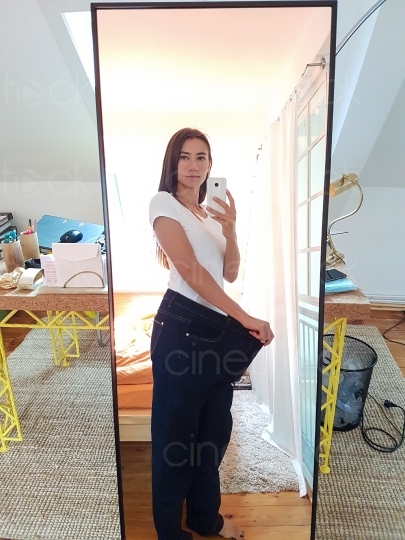 Frau mit zu großer Jeans macht ein Bild vor dem Spiegel 20160810_121216 