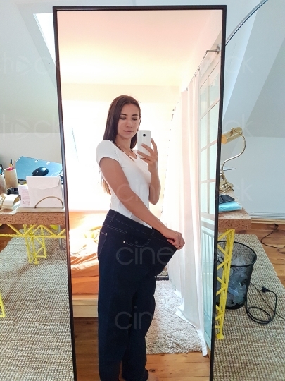 Frau mit zu großer Jeans macht ein Bild vor dem Spiegel 20160810_121218 