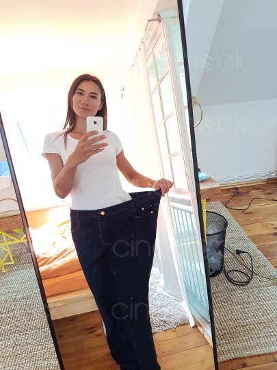 Frau mit zu großer Jeans macht ein Bild vor dem Spiegel 20160810_121237 