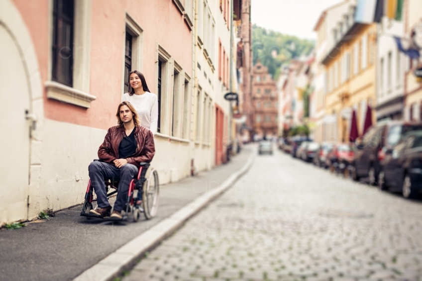 Frau schiebt Mann im Rollstuhl spazieren 20160810