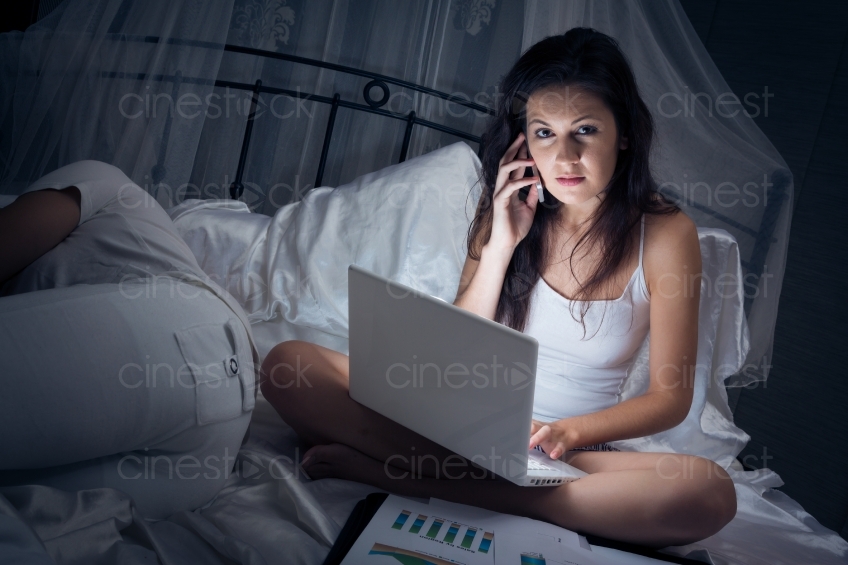 Frau sitzt arbeitend im Bett 20121130-436