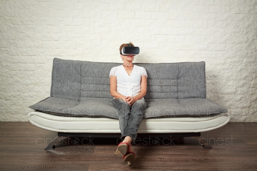 Frau sitzt auf Sofa mit VR- Brille 20160809