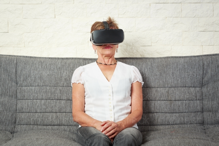 Frau sitzt auf Sofa mit VR- Brille 20160809