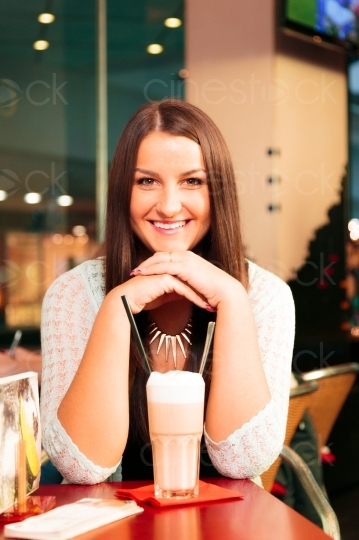 Frau sitzt lächelnd hinter Kaffee 20121117-1032