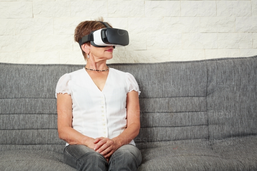 Frau sitzt mit VR- Brille auf dem Sofa 20160809