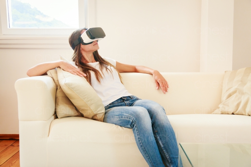 Frau sitzt mit VR-Brille auf dem Sofa 20160810
