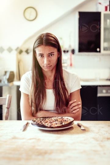 Frau sitzt vor Teller mit einer verbrannten Pizza 20160810