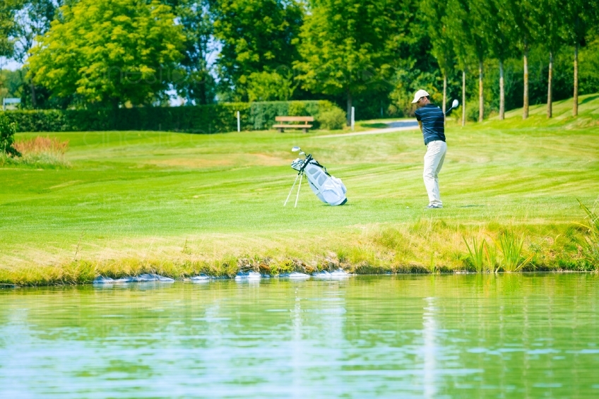 Golfer macht Abschlag am See 20120811-413