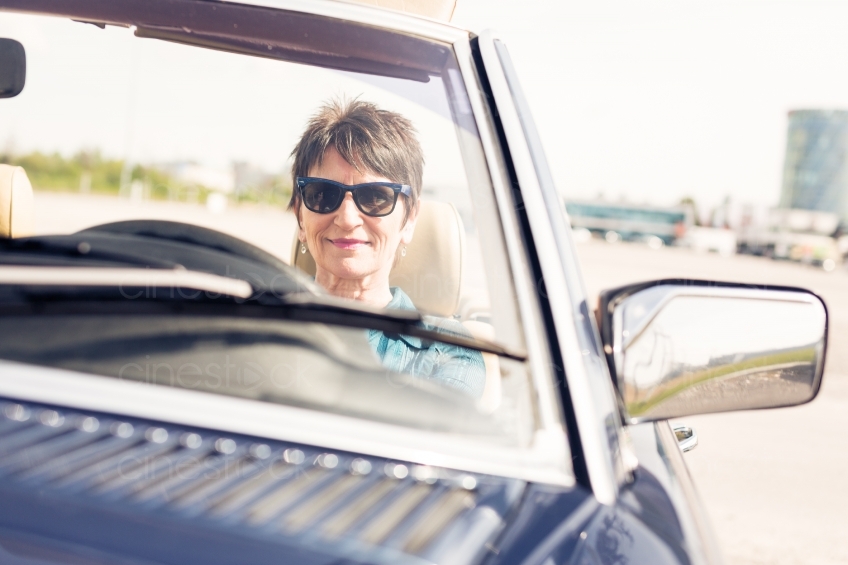 Ältere Frau am Steuer von Cabrio 20150429-0166