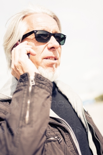 älterer Herr mit Sonnenbrille telefoniert Seitenansicht 20150429-0184