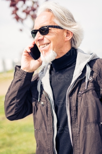 älterer Mann mit Handy und Sonnenbrille telefoniert 20150429-0181 