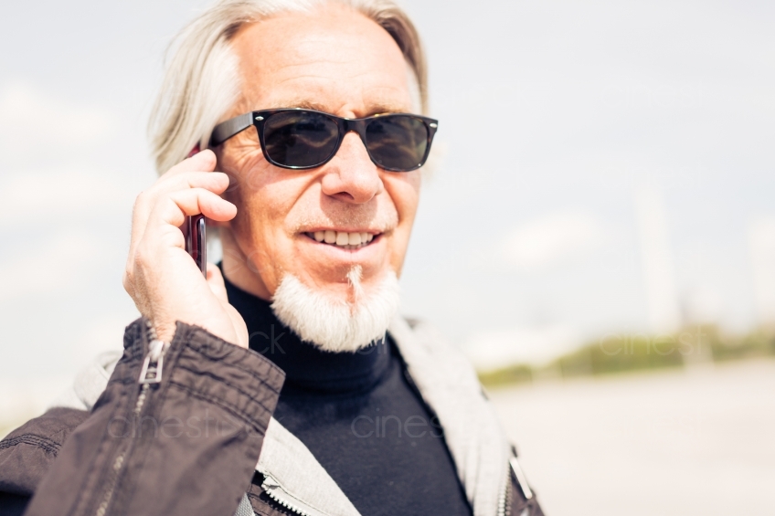 älterer Mann mit Sonnenbrille telefoniert im Profil 20150429-0186 