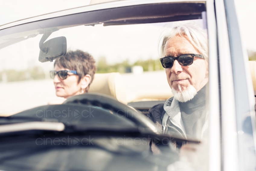 Älteres Paar in Cabrio mit Sonnenbrillen 20150429-0133