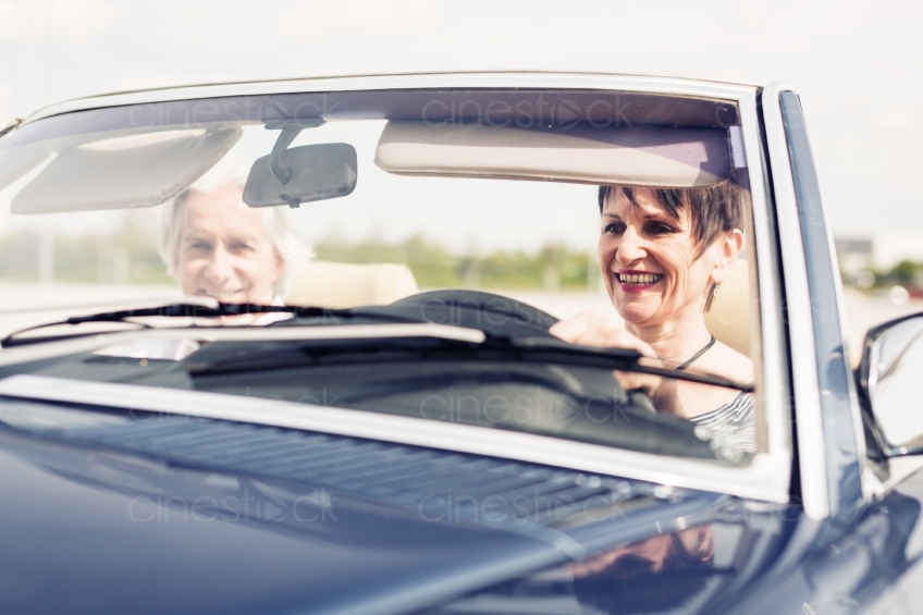 Älteres Paar lacht an Steuer im Cabrio 20150429-0360 