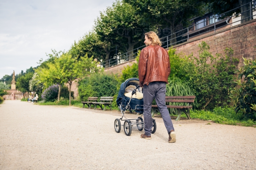 Mann geht mit Kind im Kinderwagen spazieren 20160810