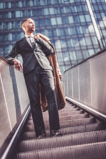 Mann im Anzug fährt auf einer Rolltreppe 20160426