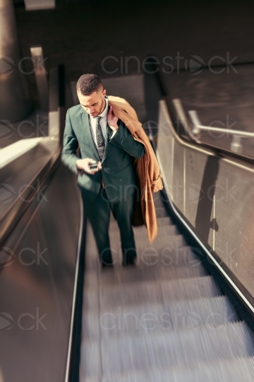 Mann im Anzug fährt auf einer Rolltreppe 20160426