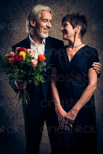 Mann im Anzug mit Blumen in den Händen und seiner Frau in Abendgarderobe 20160809