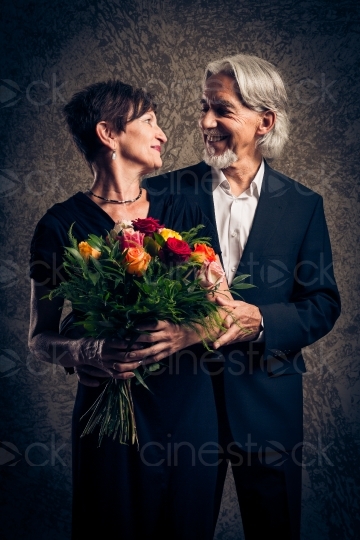 Mann im Anzug mit Blumen in den Händen und seiner Frau in Abendgarderobe 20160809