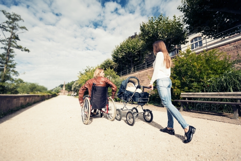 Mann im Rollstuhl und Frau mit Kinderwagen von Hinten 20160810-0274 