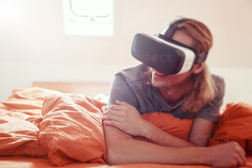 Mann liegt mit VR Brille im Bett 20160810